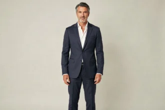 Portrait en pied d'un homme grand et élégant aux cheveux gris argenté en blazer bleu marine, illustrant la morphologie et la taille de Marc Lavoine